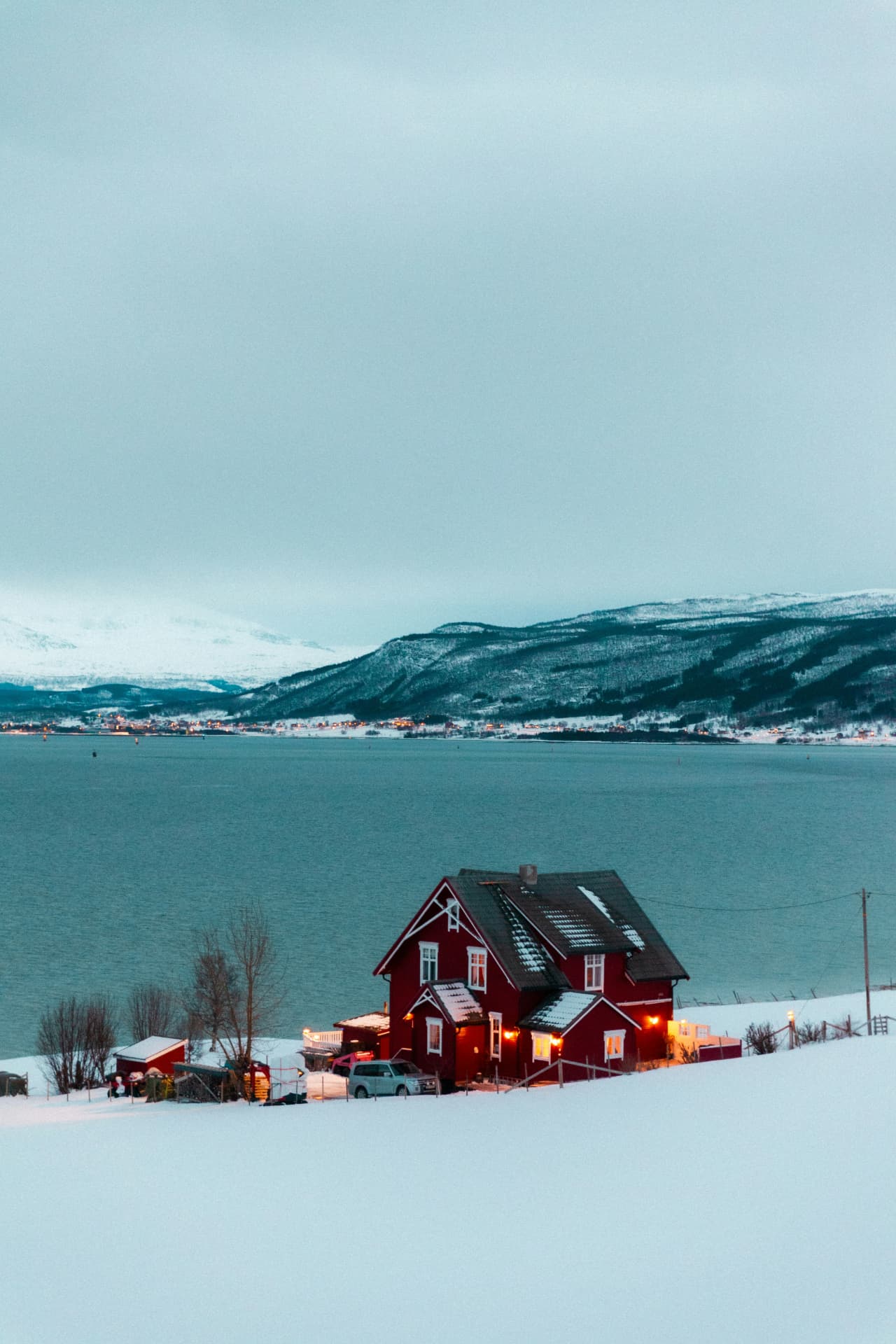 Rött hus med snötäckt tak vid vattnet i vinterljus